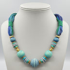 Necklace with blue and green beads on a gray stand