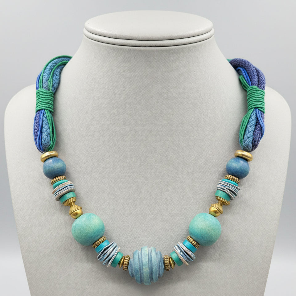 Necklace with blue and green beads on a gray stand